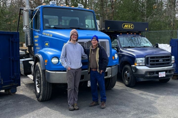 Two of the MRC crew standing in front of the company trucks