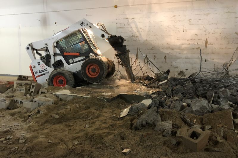 Bobcat skid-steer breaking up concrete inside a building